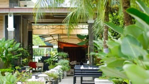 A covered outdoor area with a pathway lined with potted plants and benches, leading to an open-air seating area. - Pancur Gading Hotel & Resort (Petumbak)
