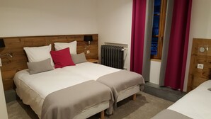 A double bed with a wooden headboard, two bedside tables, a radiator, and a window with curtains. - Hôtel du Clocher (Chamonix-Mont-Blanc)