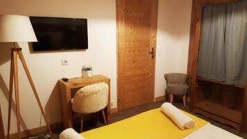 A hotel room with a bed, a desk, a chair, a television, and a window with curtains.