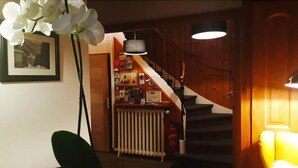 A staircase with a wooden finish, a radiator below, and a wall with framed pictures and a hanging orchid. - Hôtel du Clocher (Chamonix-Mont-Blanc)