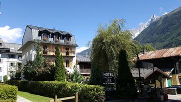 Un hotel con balcón, rodeado de vegetación y montañas.