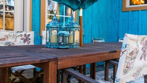 Ein Holztisch mit drei Laternen und Stühlen mit Blumenmuster.