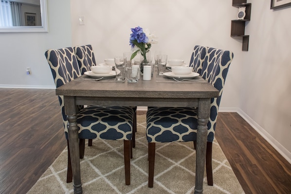 A dining table with a patterned tablecloth, surrounded by matching chairs.