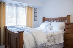 A bedroom with a wooden bed frame, white bedding, and a window with blinds. - Exclusive Private Room (Raleigh)
