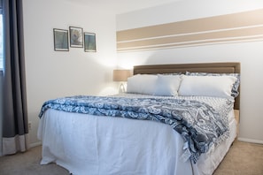 A neatly made bed with a patterned bedspread, a bedside lamp, and three framed pictures on the wall.