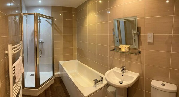 A modern bathroom with a glass-enclosed shower, a freestanding bathtub, a sink, and a toilet.