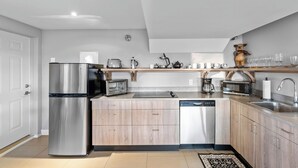 A modern kitchen with stainless steel appliances, wooden cabinets, and a built-in dishwasher.