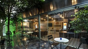 An indoor dining area with tables and chairs, a tiled floor, and glass walls. - Mezzo Hotel (Istanbul)