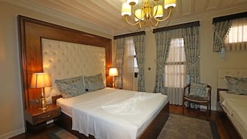 Ein geräumiges Schlafzimmer mit einem großen Bett, zwei Nachttischen mit Lampen, einer Kandelaber und einem Sessel.