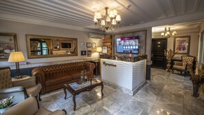 A reception area with a marble floor, a reception desk, a brown leather sofa, a coffee table, and a chandelier. - Mezzo Hotel (Istanbul)