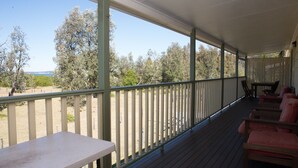 Un espacio al aire libre techado con piso de madera, una mesa y sillas.