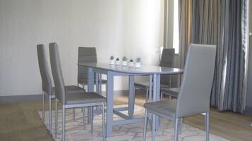 A dining area with a round table and four chairs, a small potted plant arrangement, and a light-colored rug.
