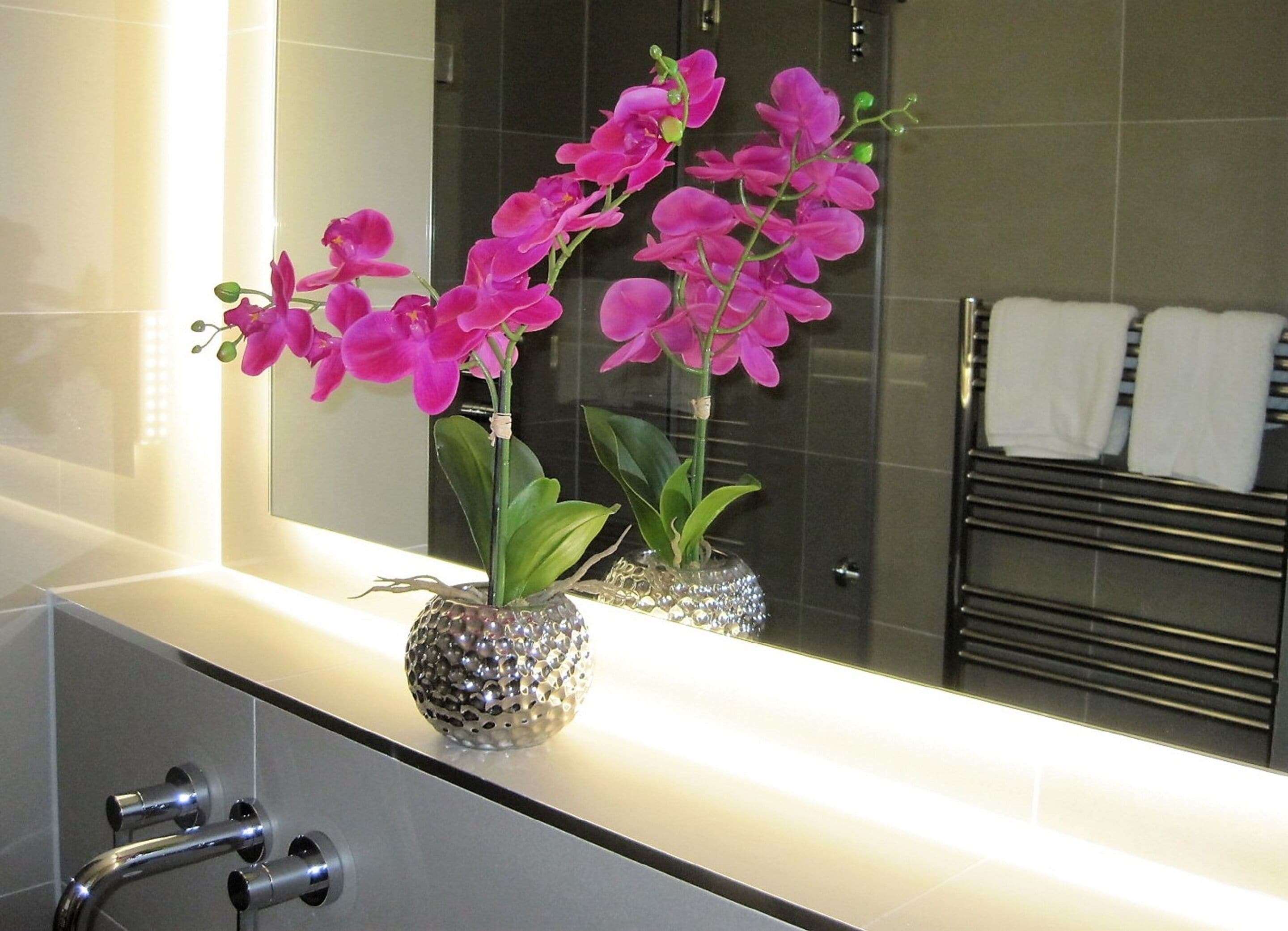 Ein Badezimmer mit Spiegel, Waschbecken und Handtuchhalter.