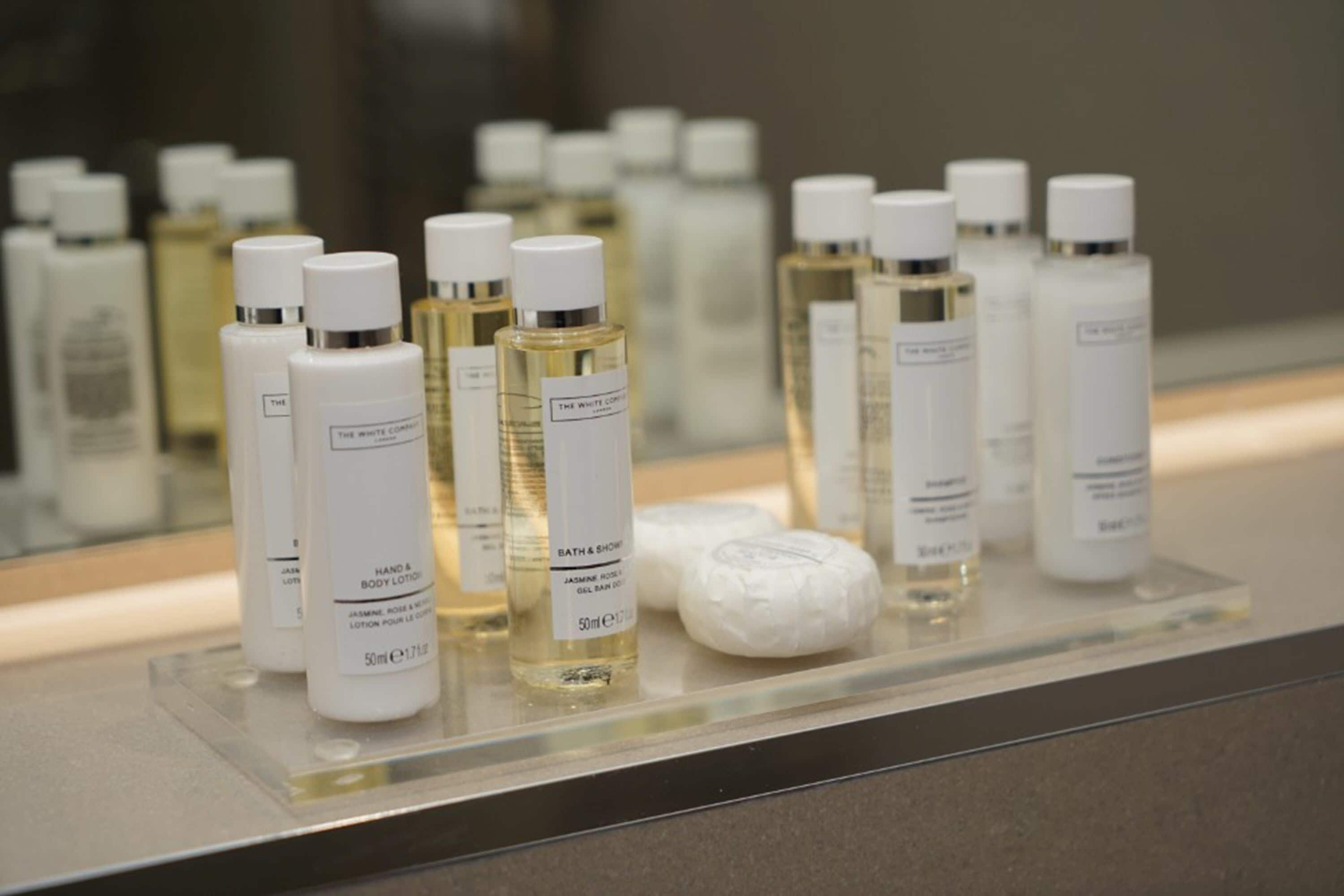 A display of various toiletries including bottles of lotion and soap on a glass shelf.