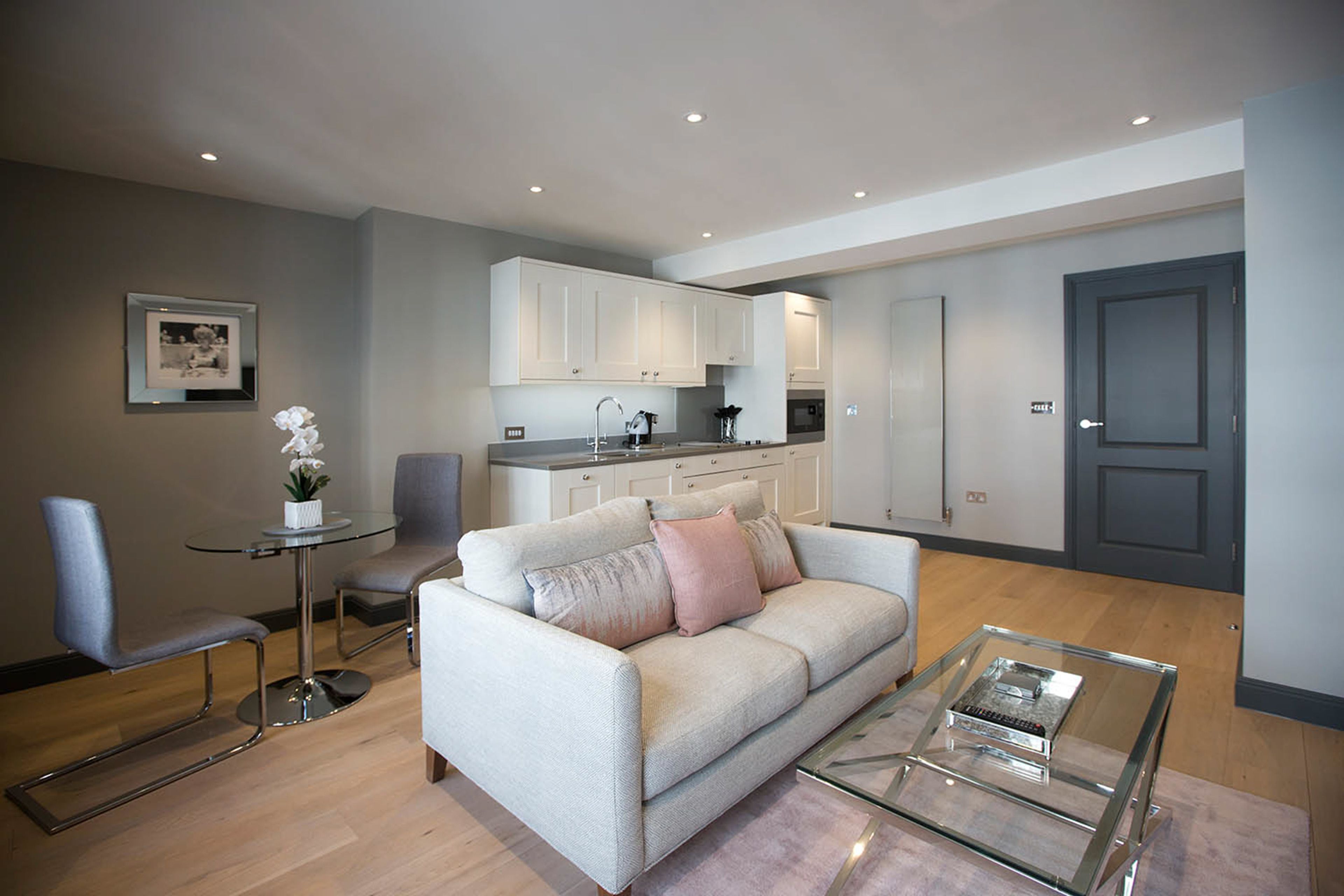 A modern living room with a sofa, coffee table, and a small dining table with chairs.