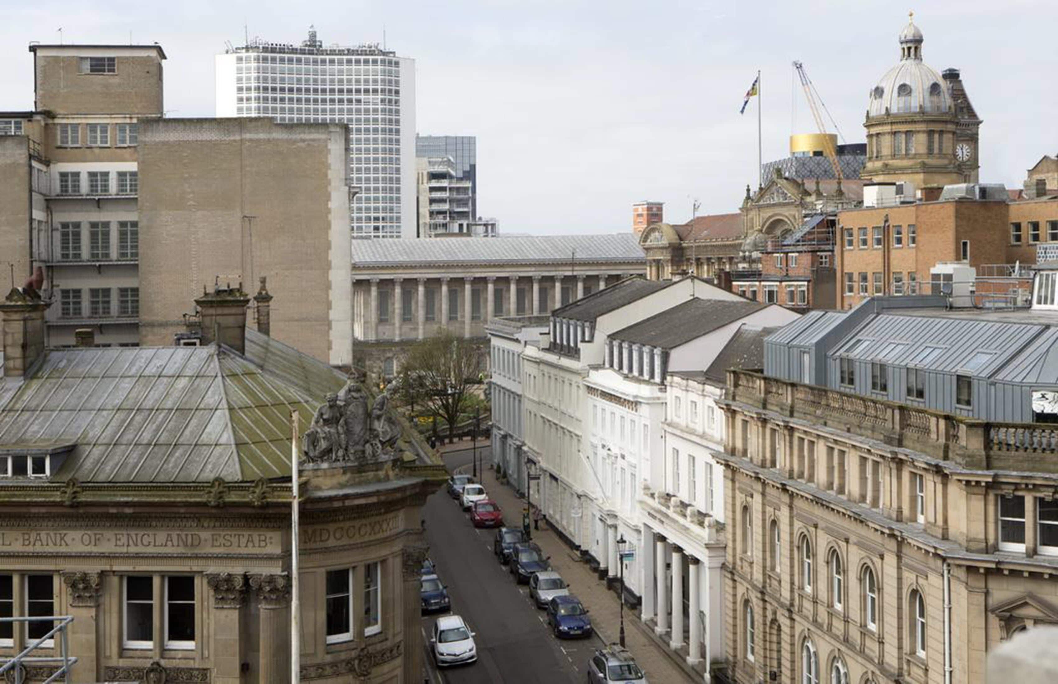 Una vista di una strada con edifici storici, tra cui una banca e un palazzo con una cupola.