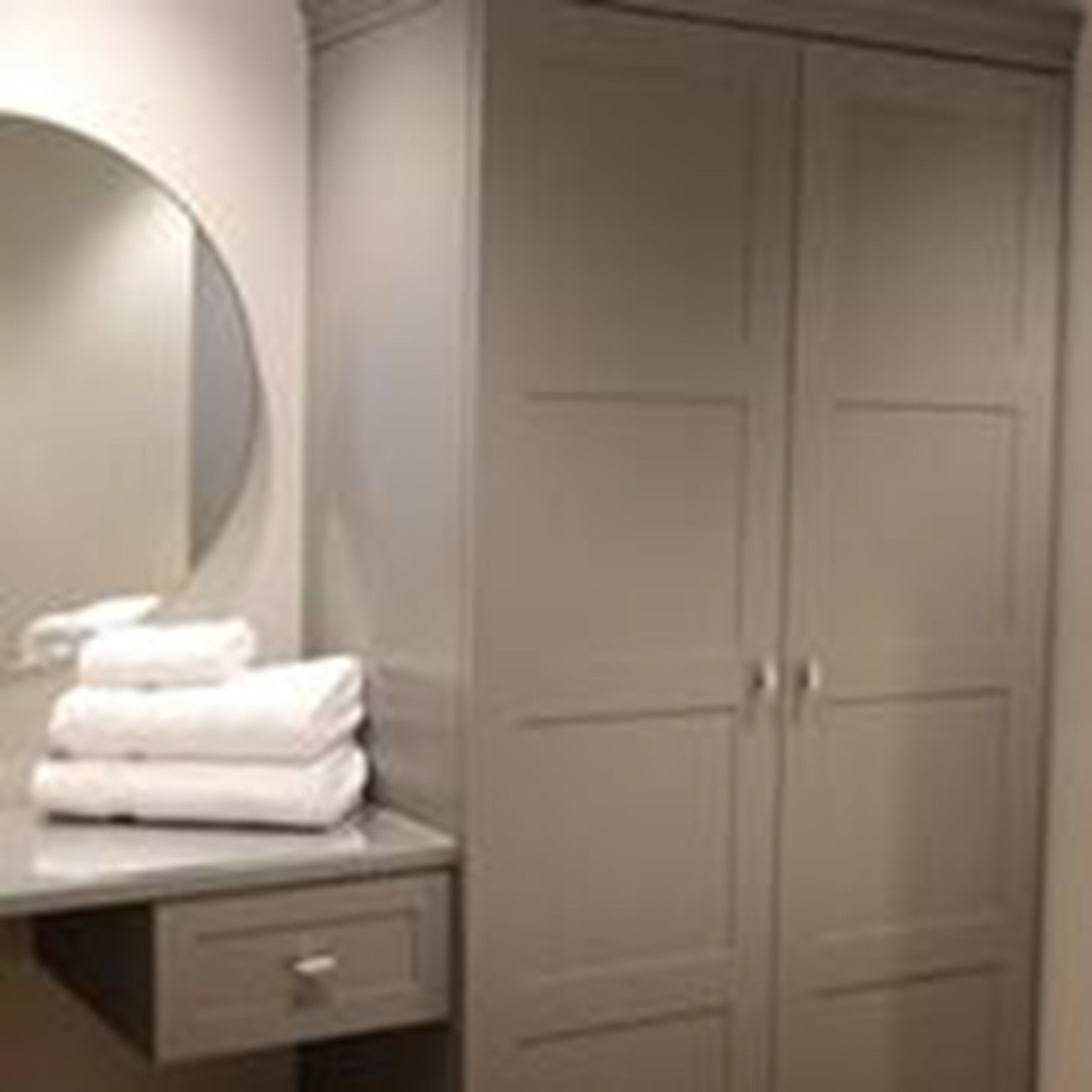 A bathroom with a mirror, a towel rack, and a wardrobe.