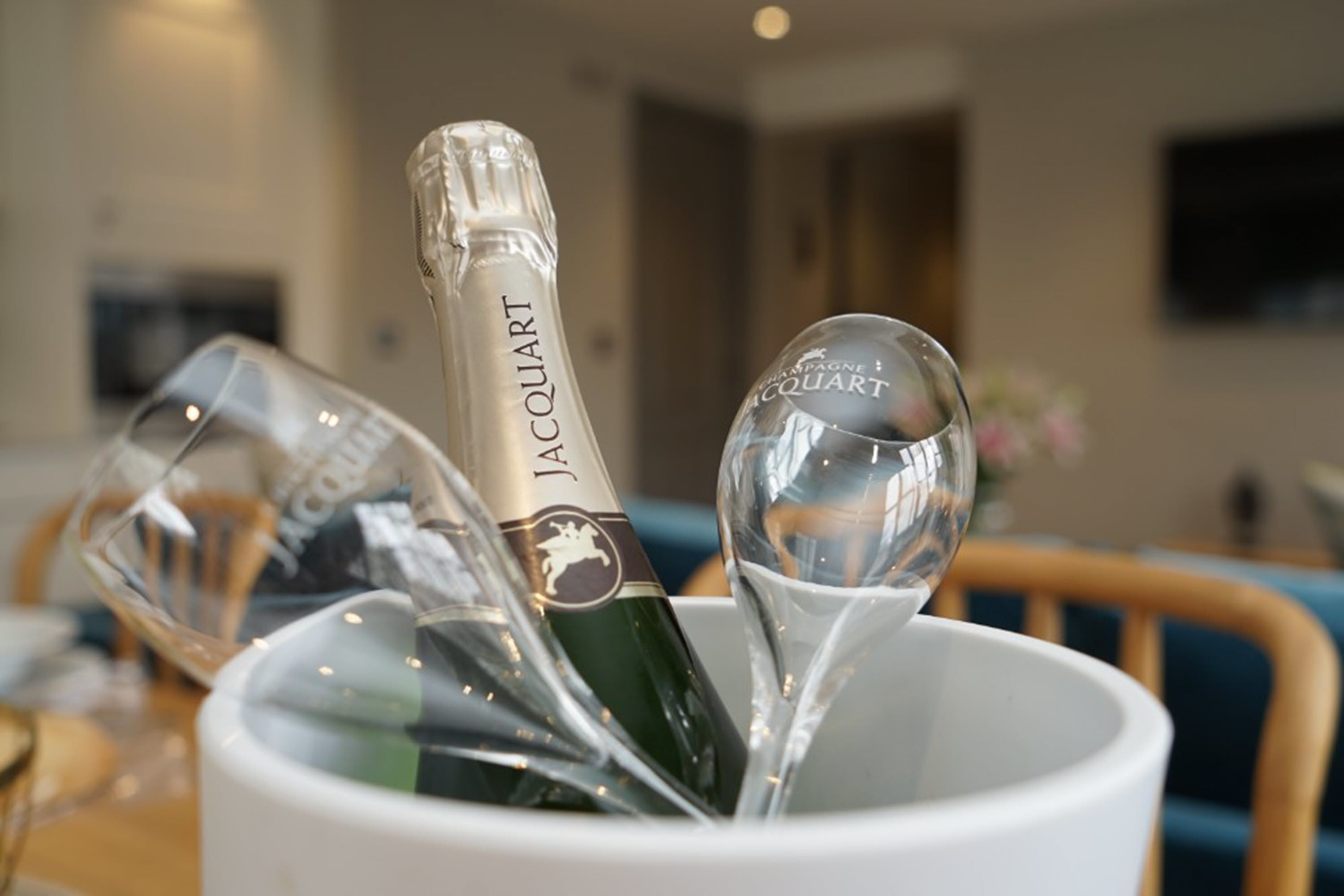 A bottle of champagne in a white cup with a glass.
