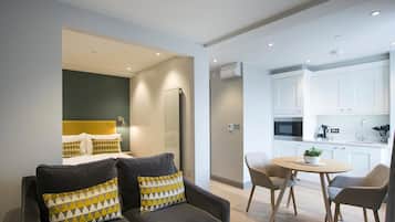 Un apartamento moderno con una sala de estar que incluye un sofá y una mesa de comedor con sillas.