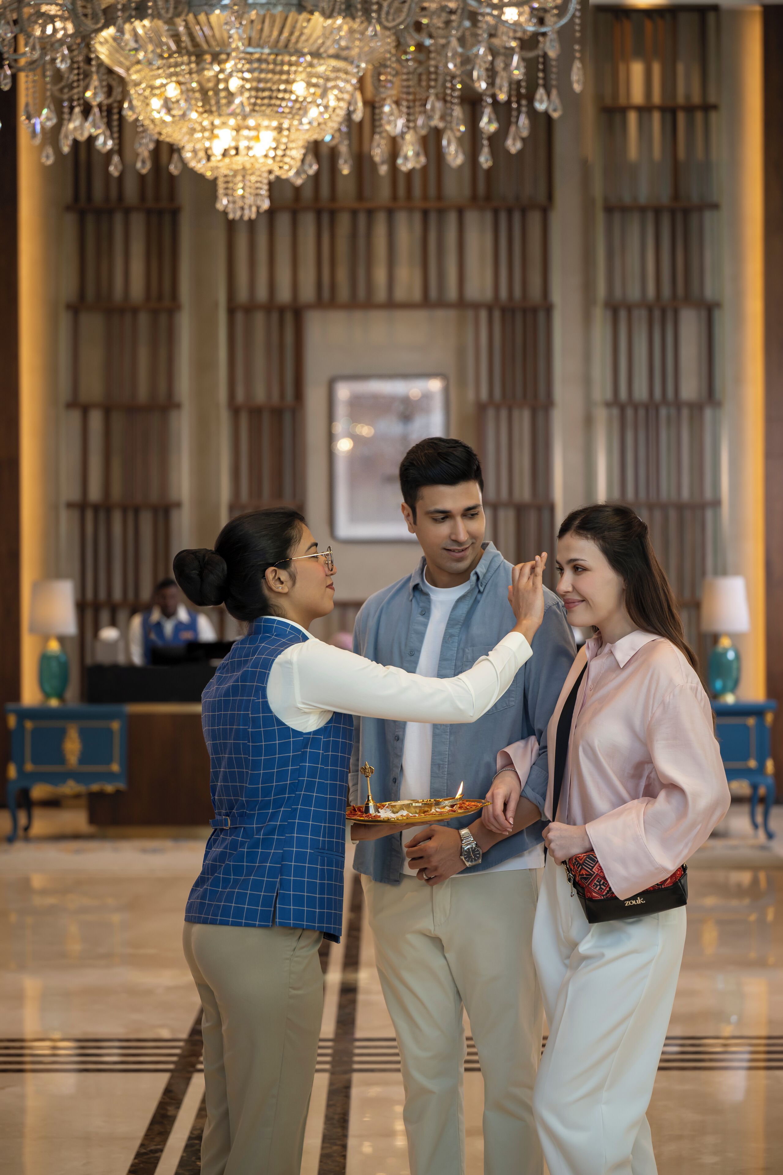 Eine Lobby mit einer Kandelaber, einer Rezeption und einem Check-in-Schalter.