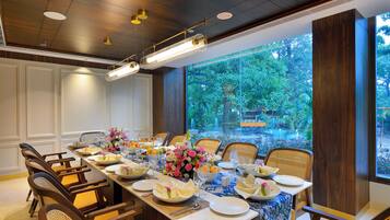 Comedor con una mesa larga dispuesta para una comida, rodeada de sillas, y vistas a zonas verdes al exterior.