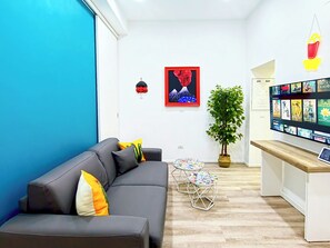 A modern living room with a grey sofa, a small round table, and a potted plant.
