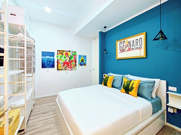 A bedroom with a bed, a blue accent wall, and three artworks.