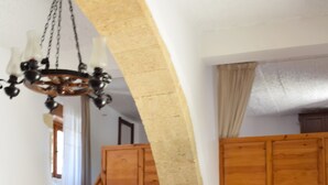 Un coin repas avec une table dressée pour deux personnes, un lustre, des meubles en bois et un escalier.