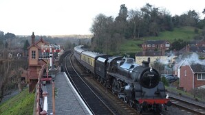 A steam locomotive at a railway station with a platform and buildings in the background. - Severn Valley Guest House (Bewdley)