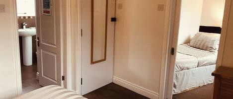 A bedroom with a bed, a bedside table, a mirror, and a door leading to a bathroom.