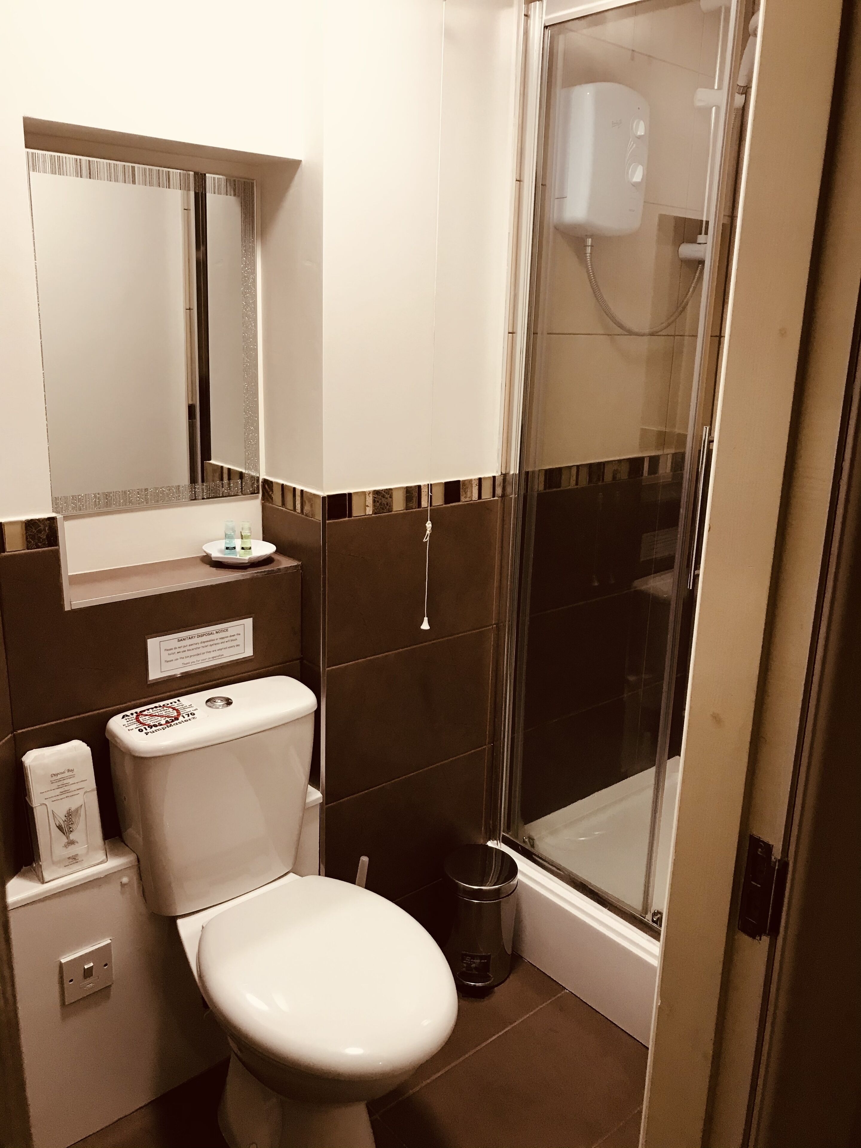 Un baño con inodoro, lavabo, espejo y cabina de ducha.