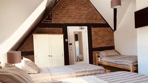 A bedroom with a sloped ceiling, a wooden bed, a small wooden bench, and a wardrobe. - Severn Valley Guest House (Bewdley)