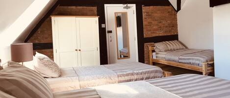 A bedroom with a sloped ceiling, a wooden bed, a small wooden bench, and a wardrobe.