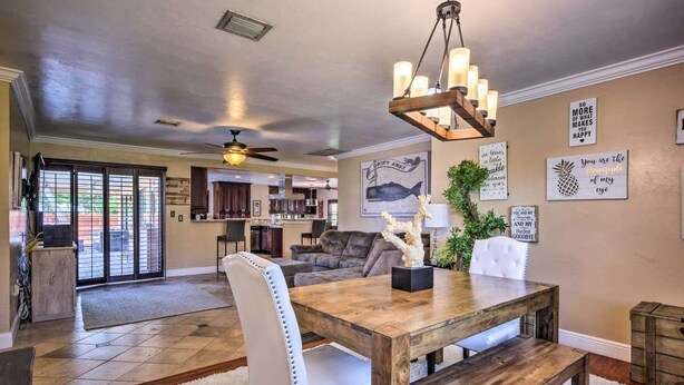 A spacious living area with a wooden dining table, white upholstered chairs, and a ceiling fan. - 2 Miles From The Beach! Resort Style Backyard, Pool, Private Tiki Bar & Spa (Bonita Springs)