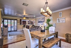 A spacious living area with a wooden dining table, white upholstered chairs, and a ceiling fan. - 2 Miles From The Beach! Resort Style Backyard, Pool, Private Tiki Bar & Spa (Bonita Springs)