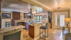 A spacious kitchen with granite countertops, dark wooden cabinets, and a large island with bar stools. - 2 Miles From The Beach! Resort Style Backyard, Pool, Private Tiki Bar & Spa (Bonita Springs)