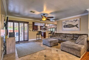 A spacious living room with a large sectional sofa, a ceiling fan, and a kitchen in the background. - 2 Miles From The Beach! Resort Style Backyard, Pool, Private Tiki Bar & Spa (Bonita Springs)