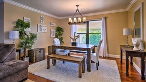 A living room with a wooden dining table, two chairs, a sofa, and a chandelier. - 2 Miles From The Beach! Resort Style Backyard, Pool, Private Tiki Bar & Spa (Bonita Springs)