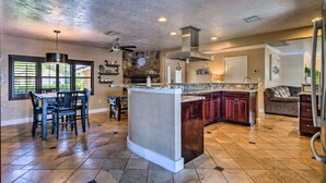 A spacious kitchen with a central island, dark wooden cabinets, and a stone backsplash. - 2 Miles From The Beach! Resort Style Backyard, Pool, Private Tiki Bar & Spa (Bonita Springs)