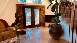 A living room with a stone fireplace, a large potted plant, a sofa, and a coffee table with decorative items. - California Dreamin' Upscale Architectural marvel / Horizon ocean view on 3 acres (Arroyo Grande)