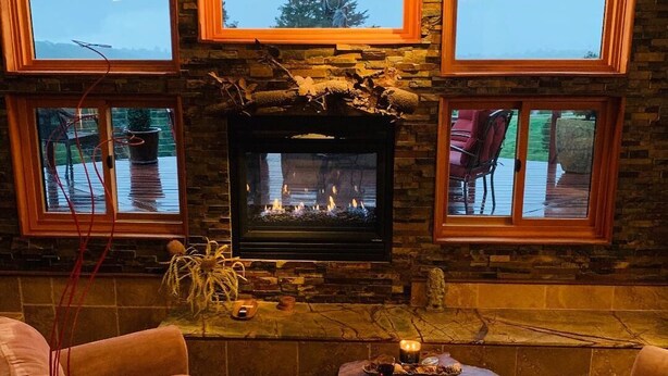 A cozy living room with a stone fireplace, comfortable seating, and large windows offering a view. - California Dreamin' Upscale Architectural marvel / Horizon ocean view on 3 acres (Arroyo Grande)