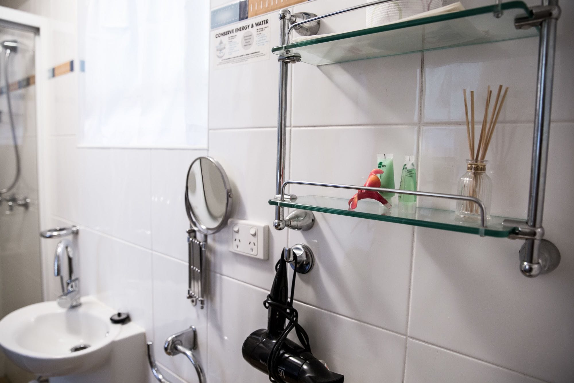 Ein Badezimmer mit einer Glasablage für Pflegeprodukte, einem Spiegel und einem Bidet.