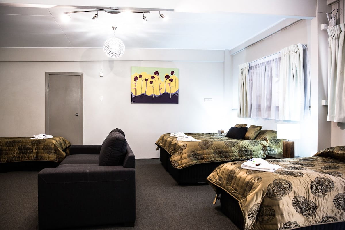 A hotel room with two single beds, a sofa, and a small table.
