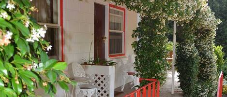 A house with a red fence, a white door, and a small patio with outdoor furniture.