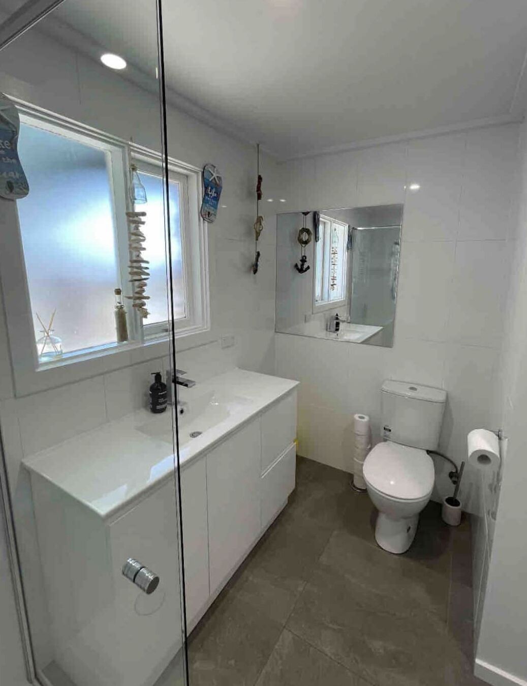 A modern bathroom with a glass shower enclosure, a white sink, and a toilet.