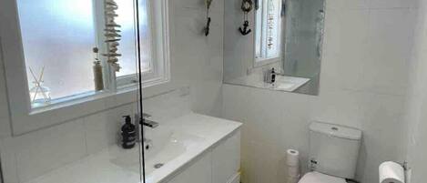 A modern bathroom with a glass shower enclosure, a white sink, and a toilet.