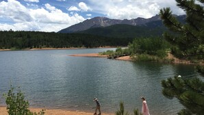 Un lago con un muelle de madera, rodeado de bosque y montañas.