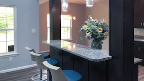 Una cocina moderna con encimera de granito, armarios oscuros y un jarrón de flores.