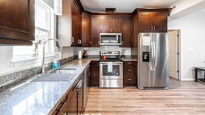 Una cocina moderna con armarios de madera oscura, electrodomésticos de acero inoxidable, encimeras de granito y horno empotrado.