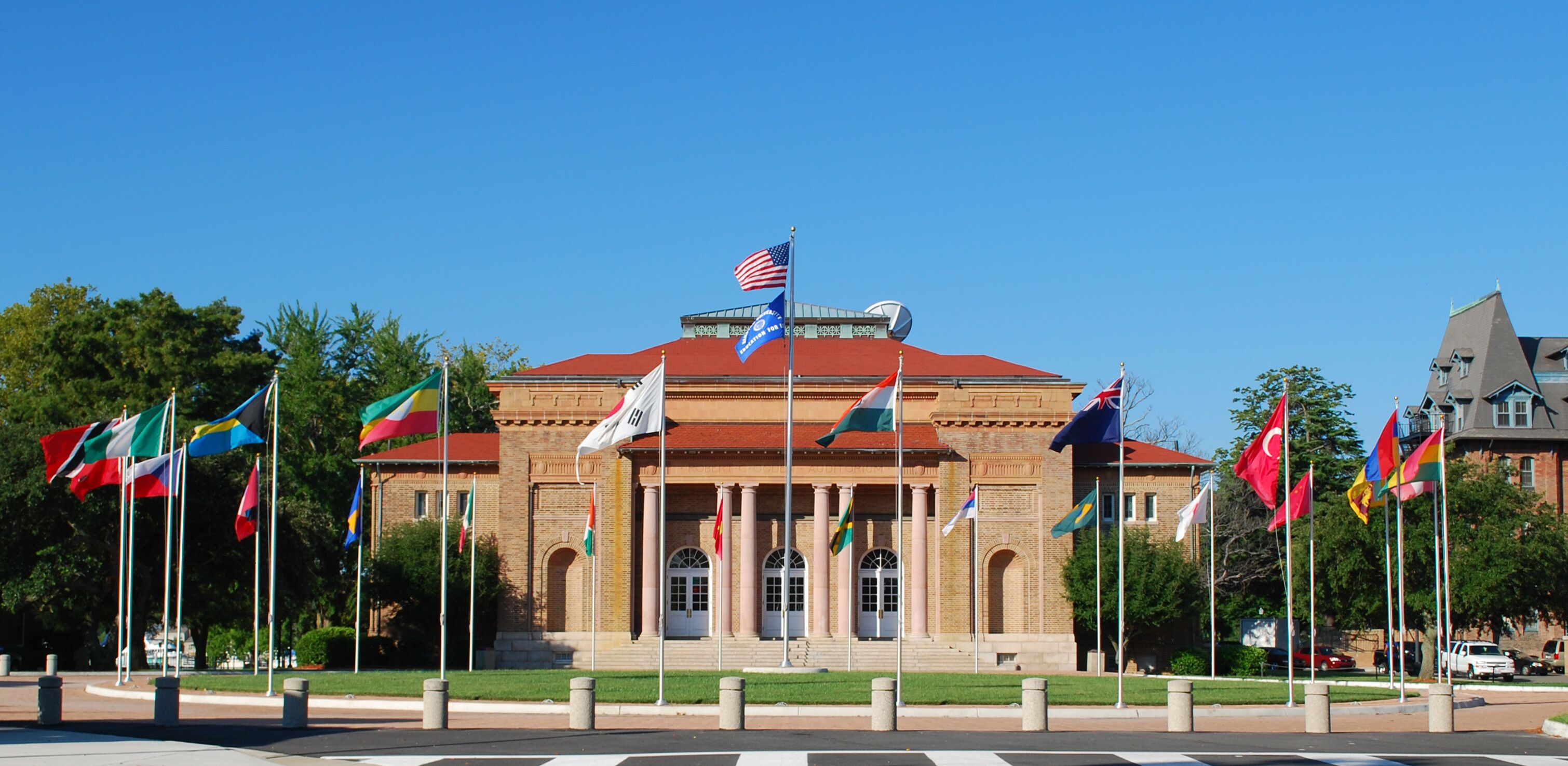 A building with a red roof and multiple flags in front.